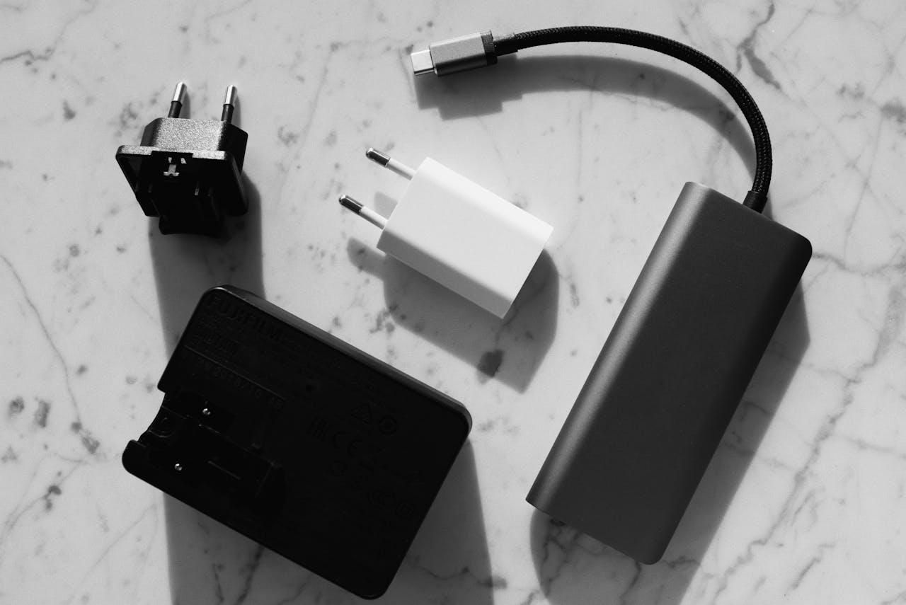 Flat lay of various electronic chargers on a marble surface with strong shadows.